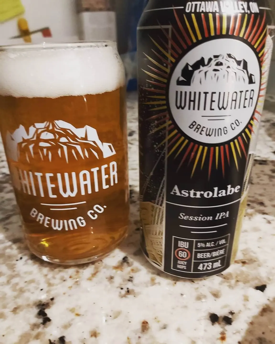 A glass of beer with foam, beside a can of beer