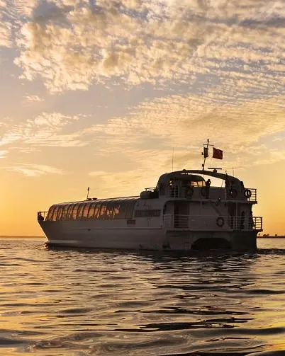 A sunset behind a boat that is cruising the waters