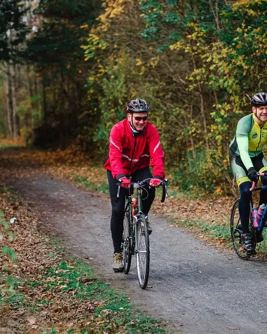 Two men smiling and cycling on a trail