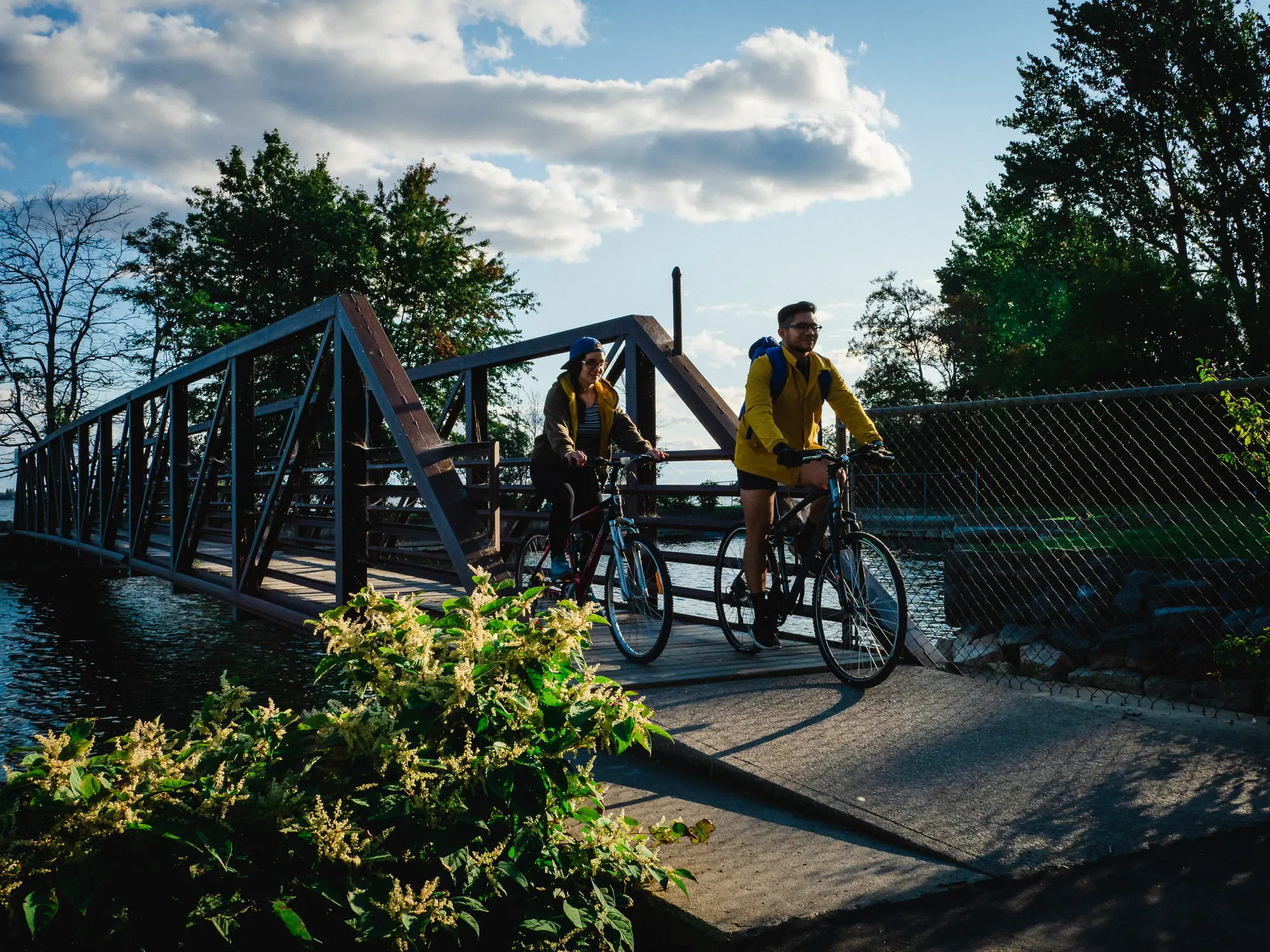 A man and a woman cycling over a small bridge