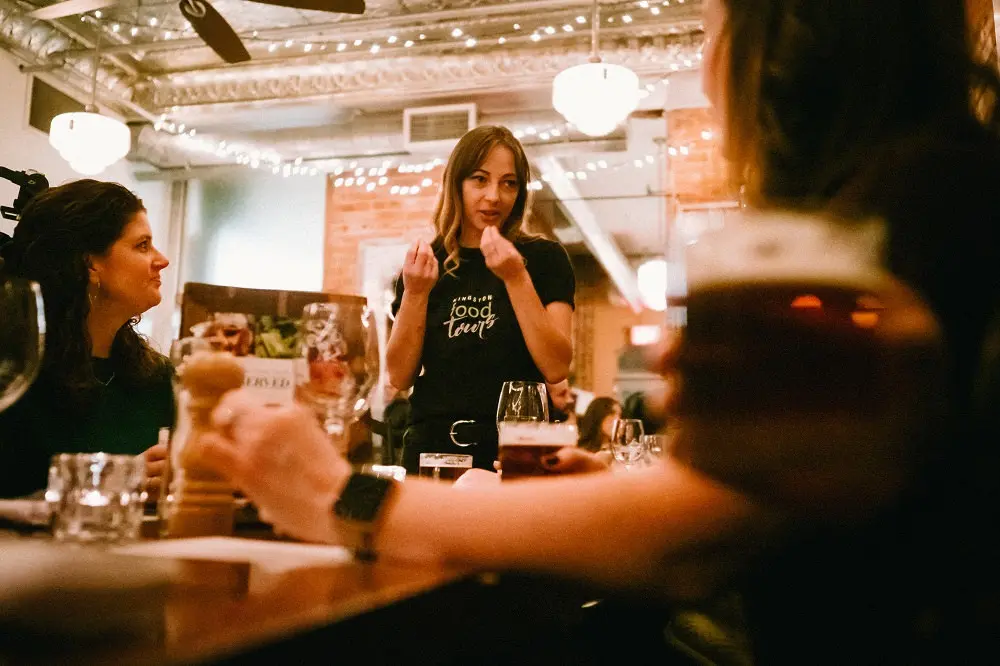 Una camarera hablando con un grupo de mujeres sentadas juntas en un restaurante