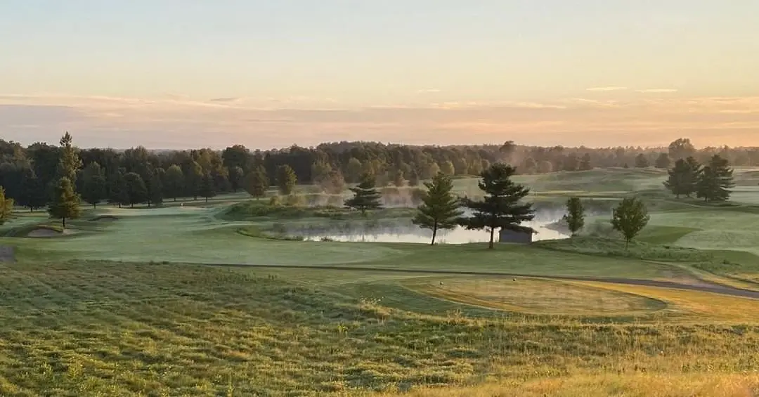Vue d'un fairway alors que la brume s'élève de l'étang sur un terrain de golf