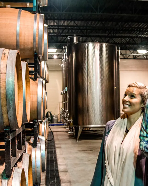 Un couple admire une pile de tonneaux de vin dans une cave viticole