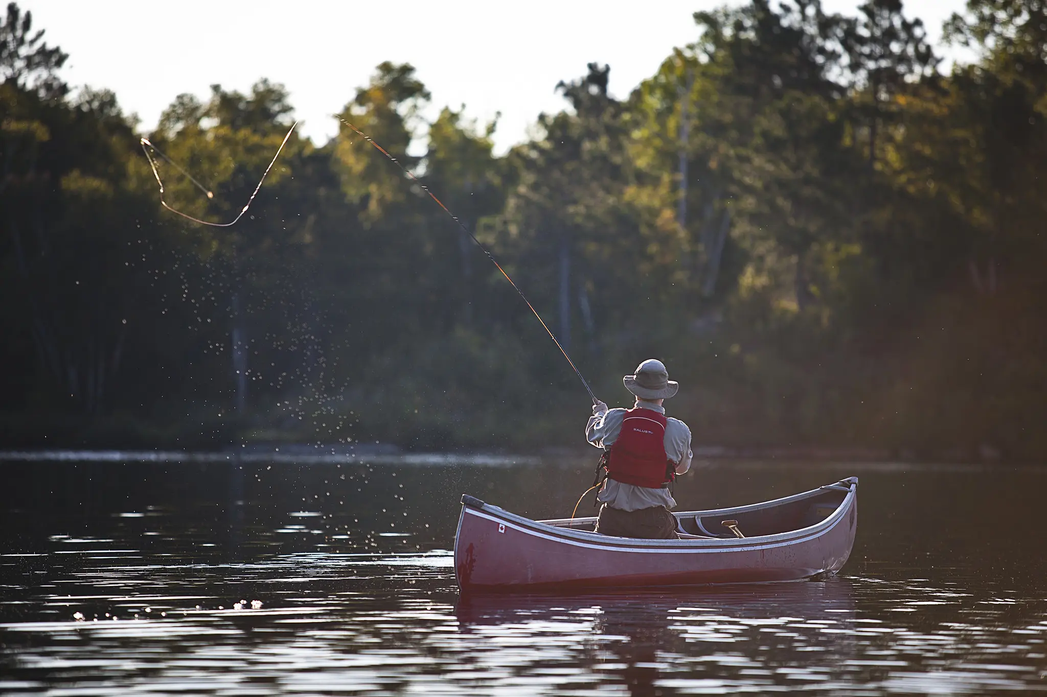 A man casting his line from a boat on a lake