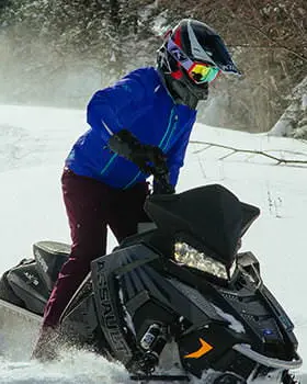 2人のスノーモービル乗りが雪の中を走る