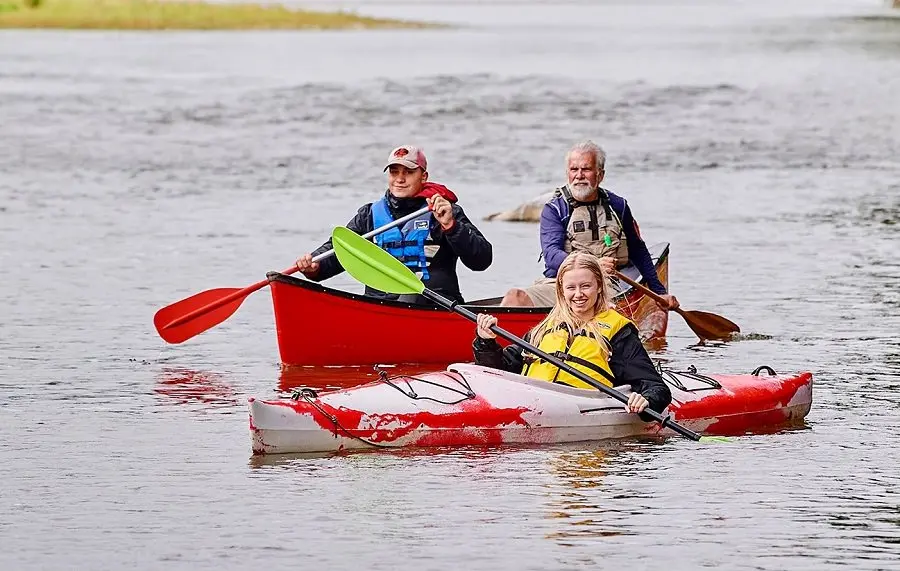 Jeune fille en kayak devant deux hommes en canot 