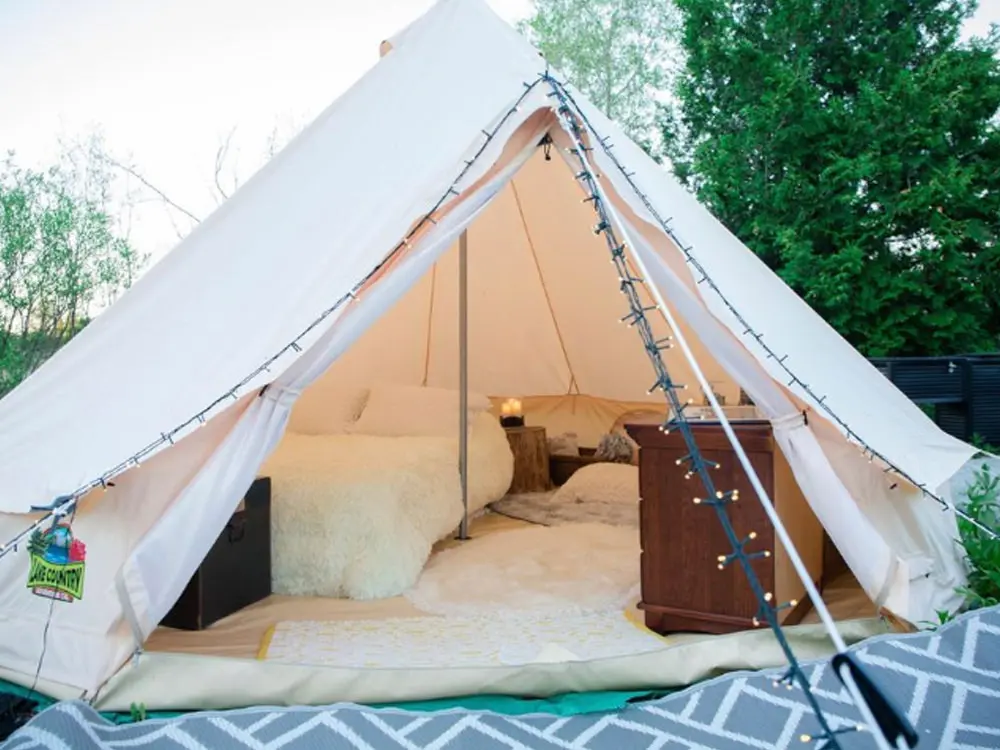 Ein gemütliches Glamping-Zelt mit weicher Bettwäsche und Möbeln