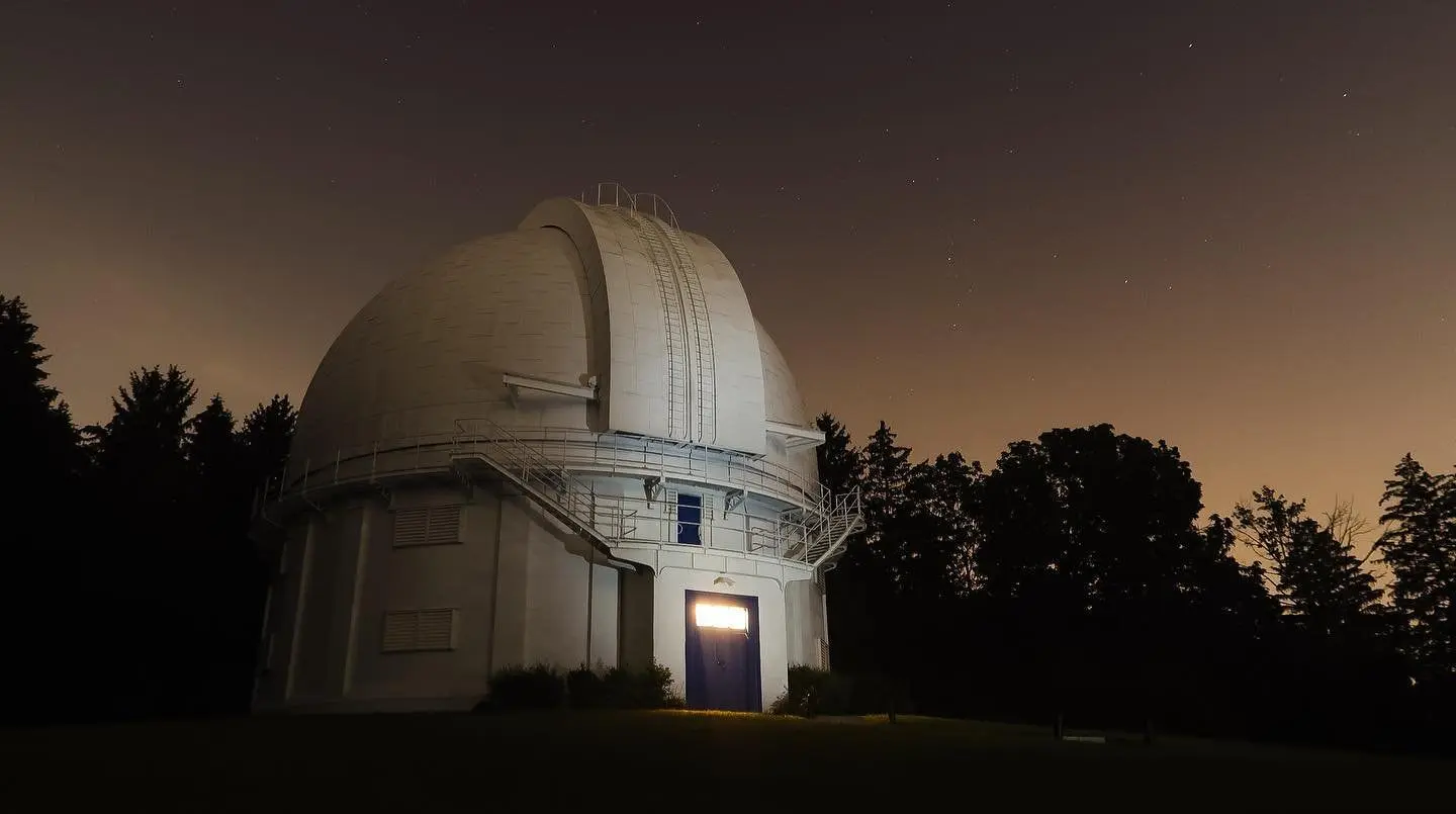 Un cielo oscuro con estrellas rodea el edificio del observatorio gris