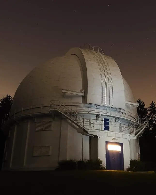 Un ciel sombre avec des étoiles entoure le bâtiment gris de l'observatoire