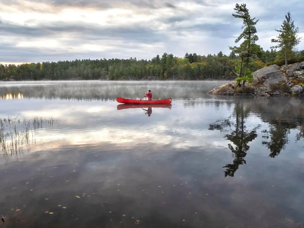 湖のカヌーを漕ぐ男