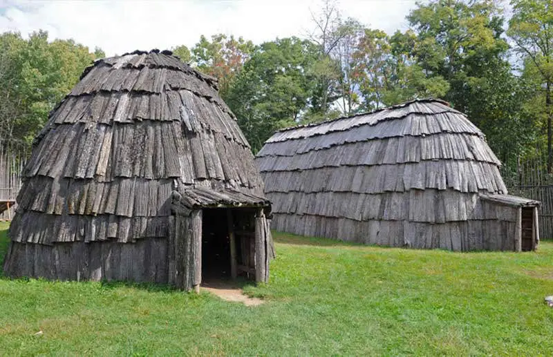 Two wooden cabins in the longhouse village