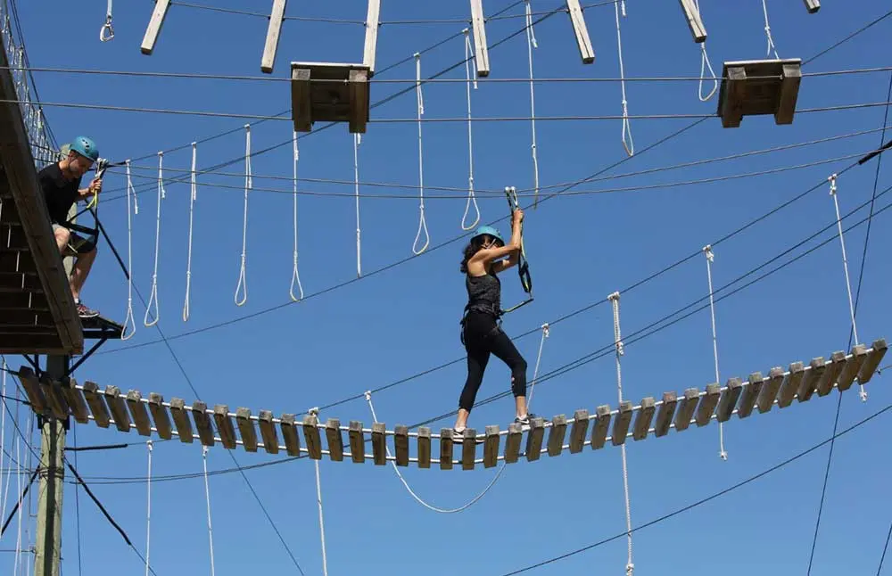 A woman walks across an aerial bridge