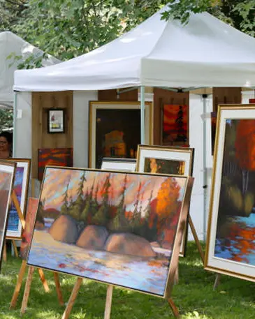 Différentes peintures entourées d’arbres et de tentes