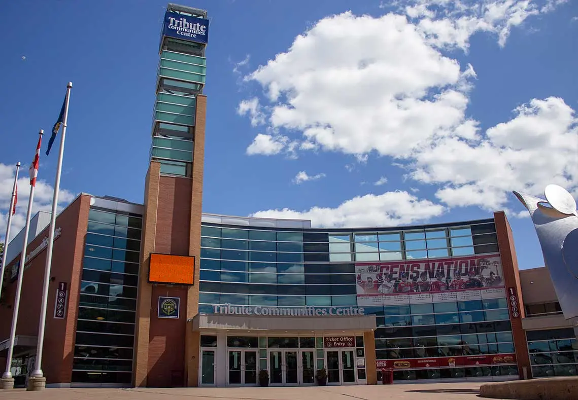 Tres postes de bandera al lado de un edificio marrón alto con muchas ventanas