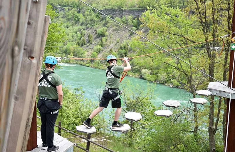 A person stepping on suspended platforms between two treetops