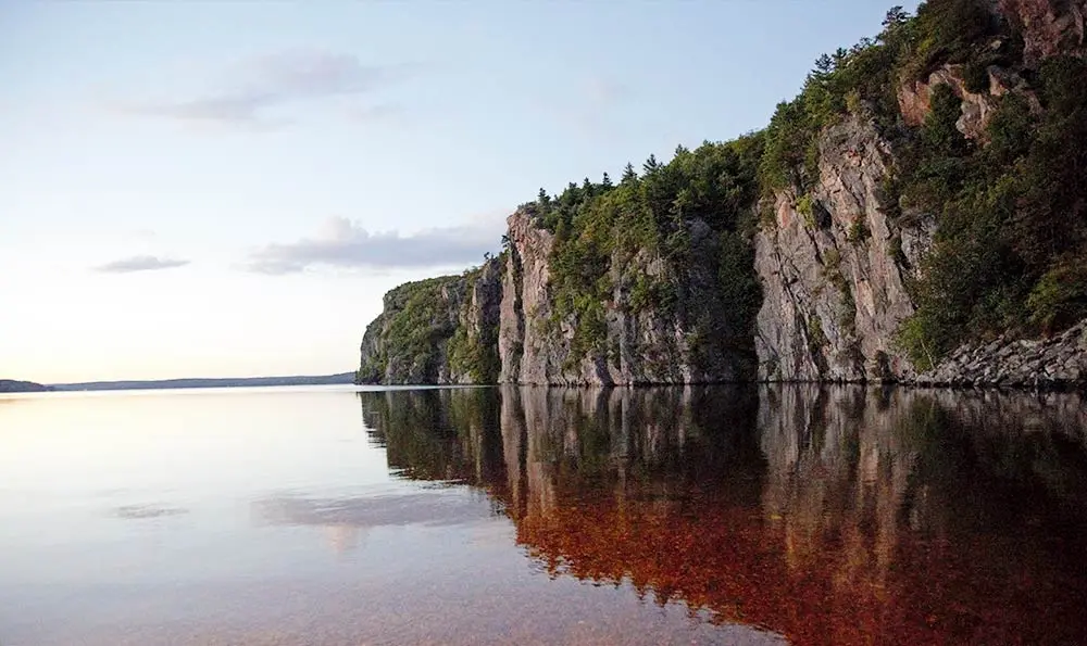본 에코 주립공원의 고요한 물 위에 거대한 울퉁불퉁한 바위가 반사된 모습.