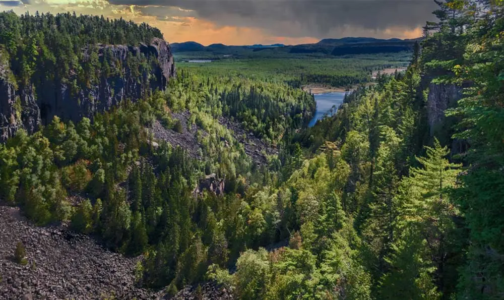 Ein weitreichender Blick auf den Ouimet Canyon mit Wald und Seen im Hintergrund.