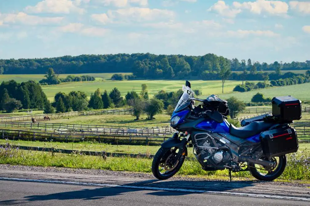 馬場を見下ろす田舎道の脇に停められた青いバイク。