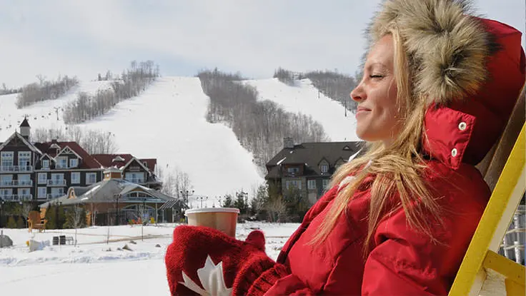 Une femme se détendant et dégustant une boisson chaude après le ski alpin