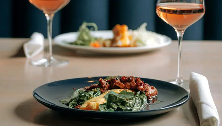 Deux assiettes de nourriture et deux verres de vin rosé sont assis sur une table