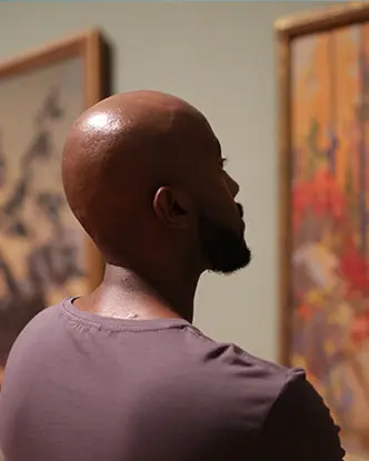 ギャラリーの壁に飾られた芸術作品を鑑賞する人々。