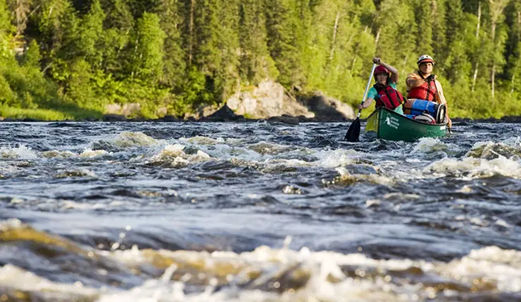 ミシナビ川の荒波をカヌーで下る二人。