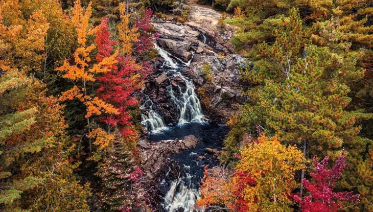 Une cascade pittoresque entourée de feuillage d'automne.