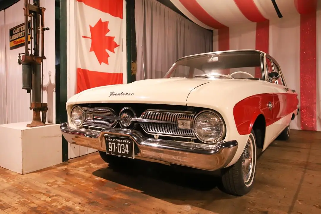 A vintage red and white car is showcased with the Canadian flag