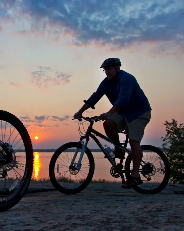 Deux cyclistes admirent le suset sur le lac.