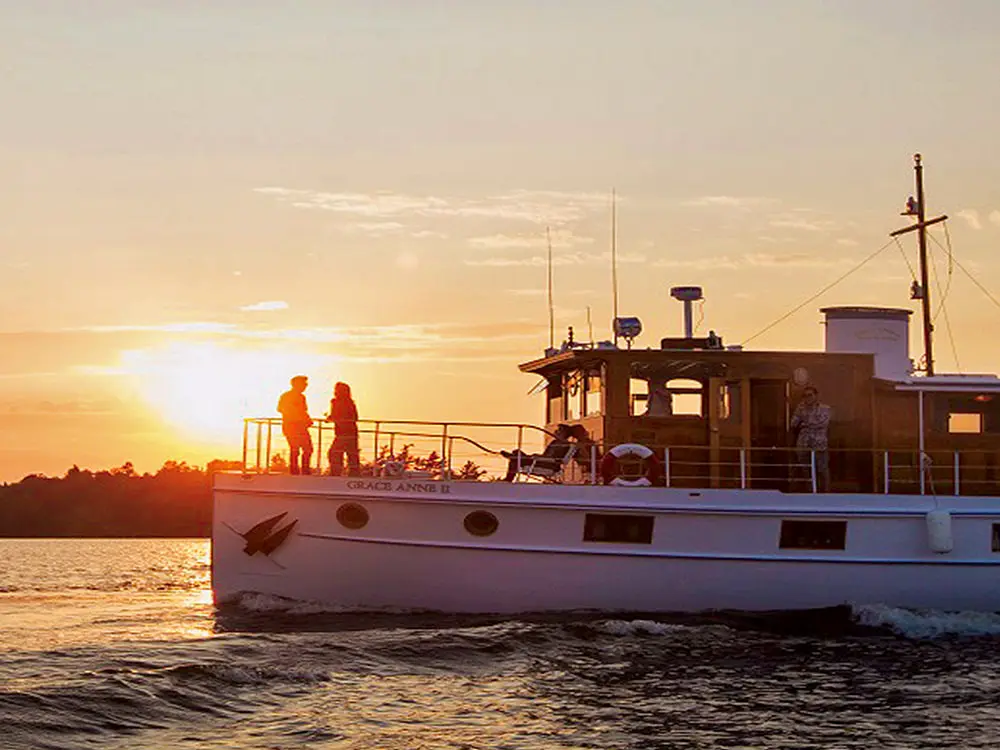 A sightseeing cruise sails past a stunning sunset.
