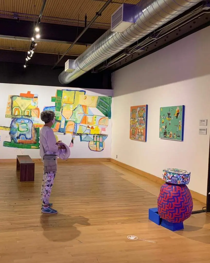 Una mujer que lleva una máscara admira el arte en una habitación.