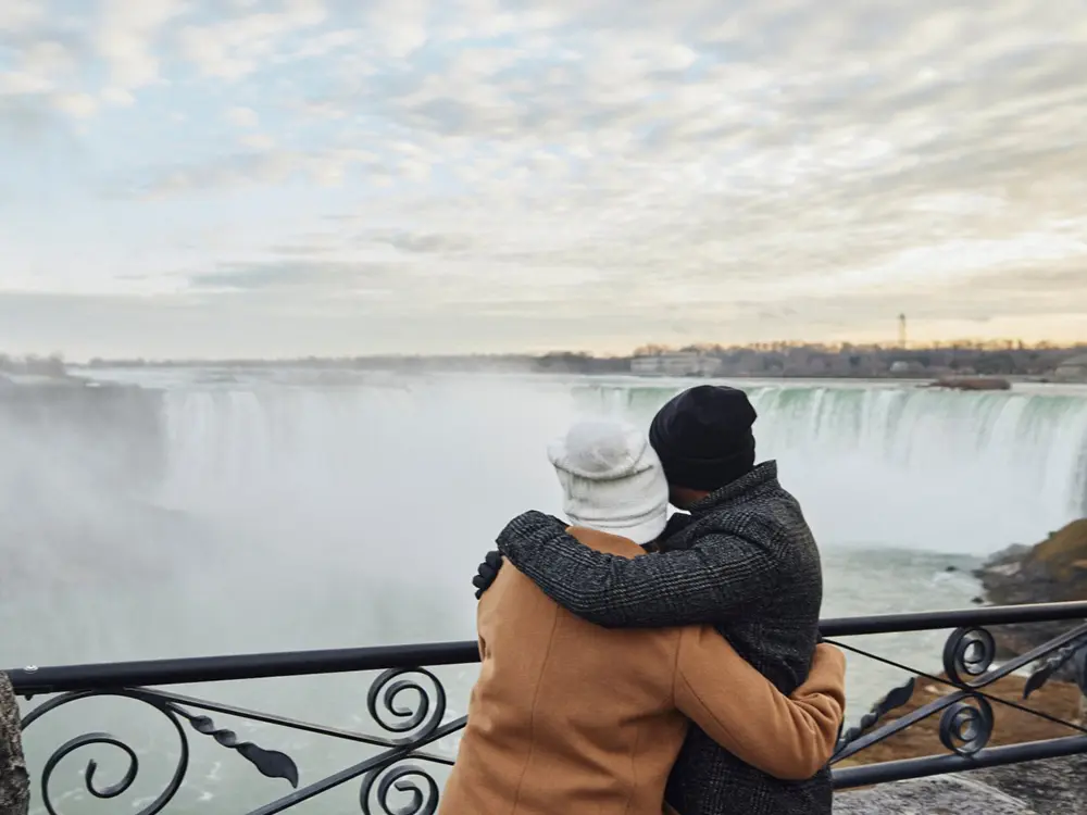 Ein Paar umarmt sich im Winter an den Niagarafällen.