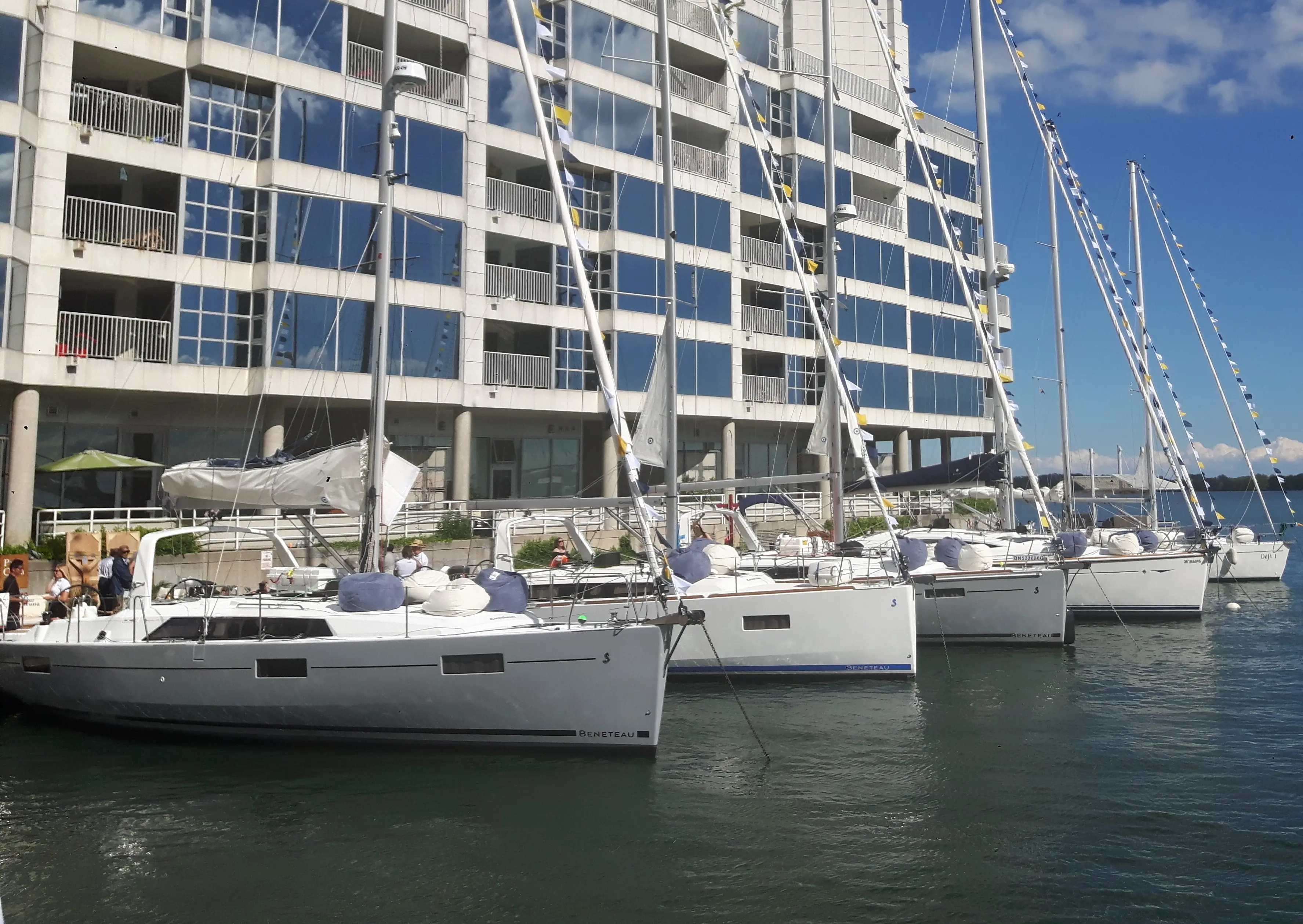 Un groupe de voiliers amarrés autour d'un quai devant un immeuble en copropriété