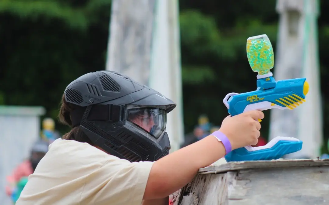 긴 금발 머리에 검은색 마스크를 한 여성이 검은색 그물로 둘러싸인 지역에서 오른쪽 화살표로 활을 가리키고 있습니다. 이 지역은 작은 노란색 풍선으로 가득 차 있습니다.