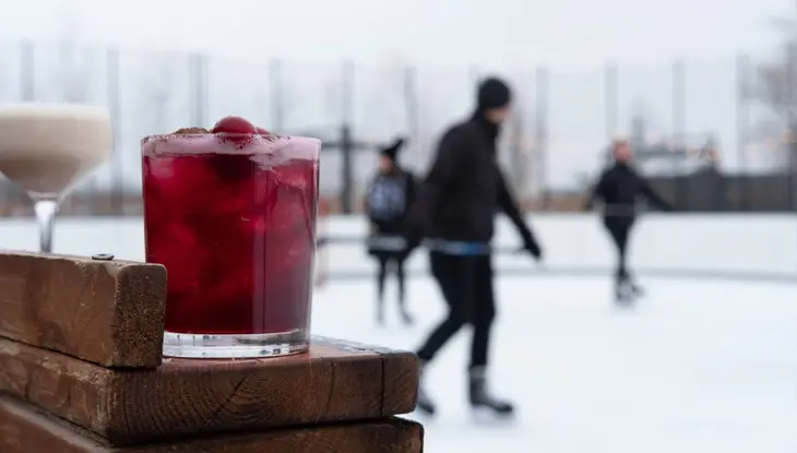 Une boisson sur une table avec des gens patinant en arrière-plan.