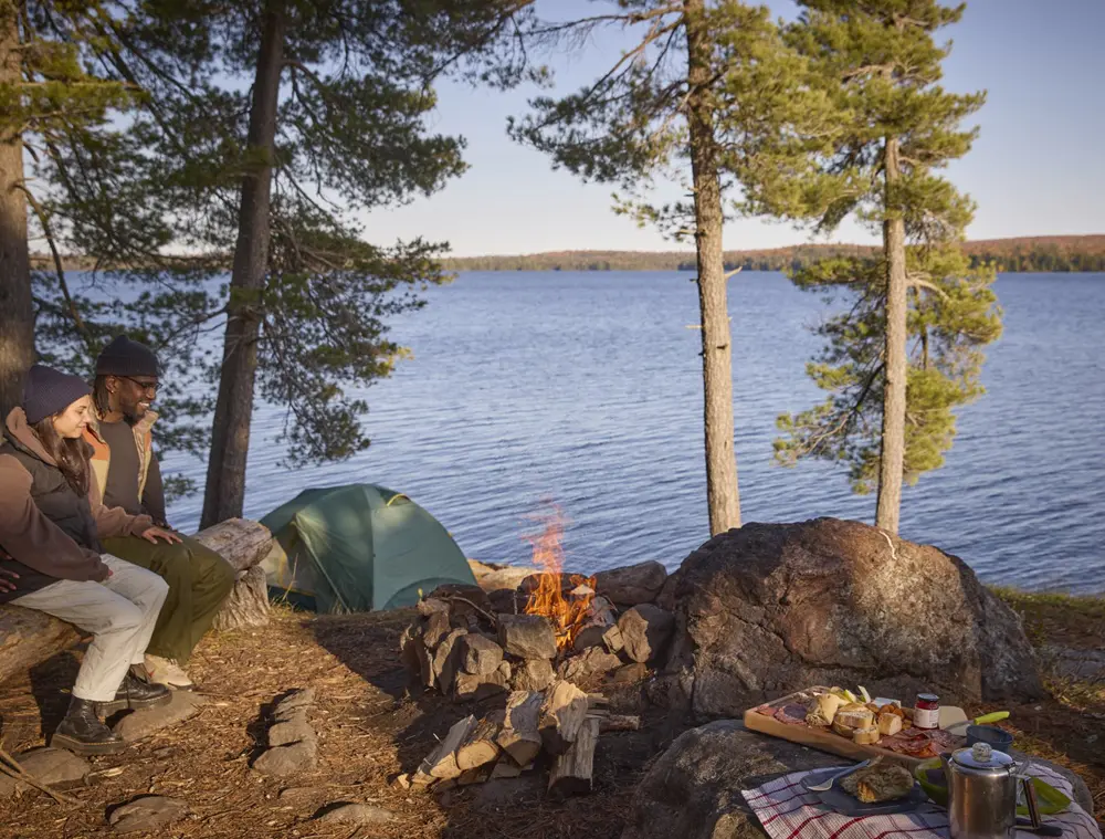 アルゴンキン公園のキャンプ場で、火の前に2人が一緒に座っている。