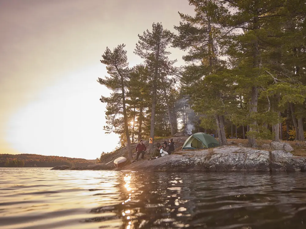 캠핑객들이 알곤퀸 공원에서 바위 해안에 앉아 일몰을 구경하고 있습니다.