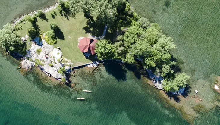 Luftaufnahme einer felsigen Küste, sauberen Gewässern und zwei Kajakfahrern im Gebiet der 1000 Inseln des Sankt-Lorenz-Stroms.