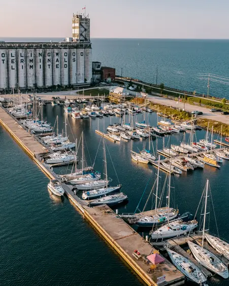 Vue aérienne de la façade portuaire de Collingwood avec ses silos terminaux historiques, des voiliers amarrés dans une marina et la baie Georgienne qui s’étend à l’horizon.