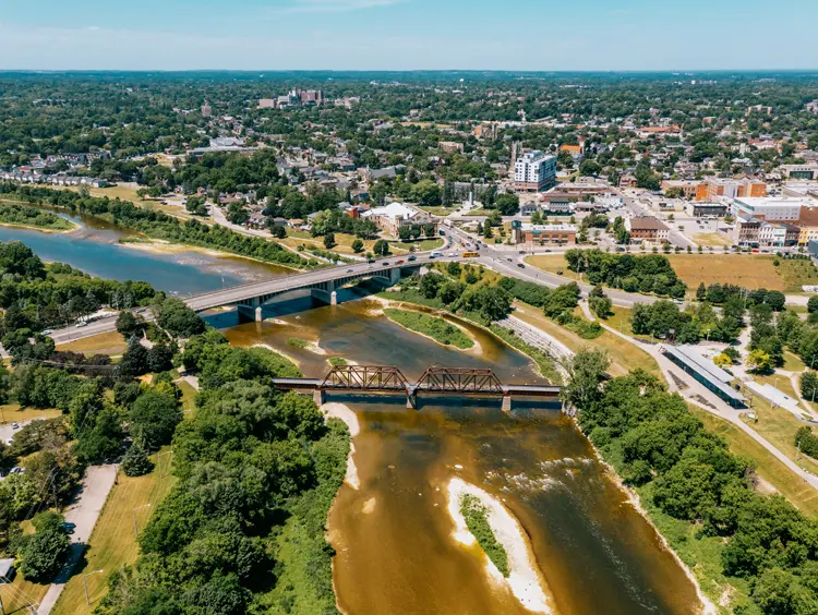 Luftaufnahme von Brantford mit der Lorne Bridge und der Eisenbahnbrücke über den Grand River, umgeben von Grünflächen und städtischen Gebäuden.