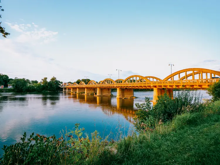 Les arches en béton du pont de la rue Argyle à Caledonia qui brillent au coucher du soleil et se réflètent sur l’eau calme.