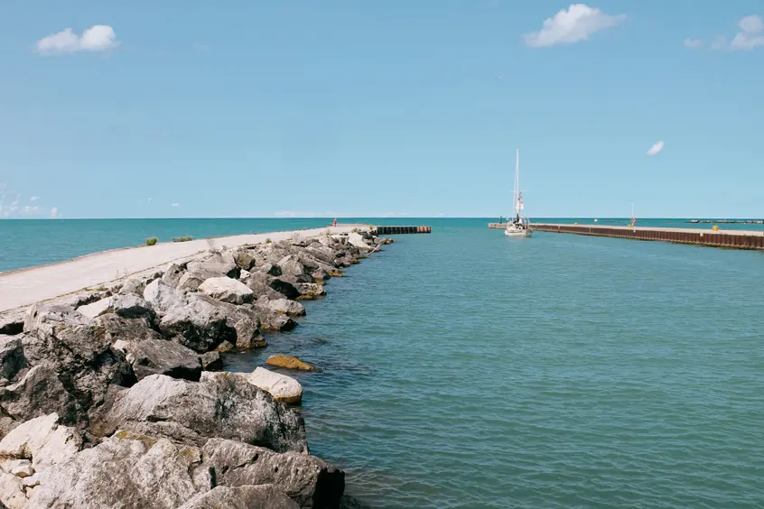 Steinerner Wellenbrecher und Pier, der sich ins türkisfarbene Wasser am Eingang zum Bayfield Harbour am Lake Huron erstreckt.