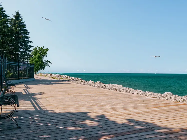 Promenade in Goderich, Ontario, entlang des türkisfarbenen Wassers des Lake Huron unter einem strahlend blauen Himmel.
