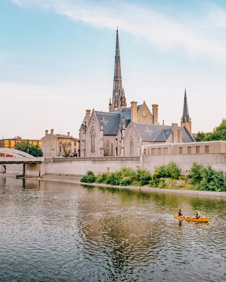 Eine Kanufahrt auf dem Grand River in der Innenstadt von Cambridge, Ontario, vorbei an historischen Gebäuden und Kirchtürmen im Abendlicht.