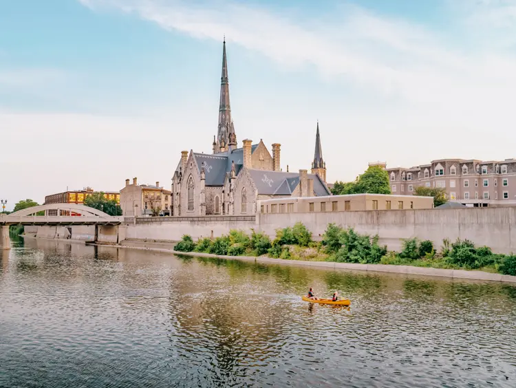 Eine Kanufahrt auf dem Grand River in der Innenstadt von Cambridge, Ontario, vorbei an historischen Gebäuden und Kirchtürmen im Abendlicht.