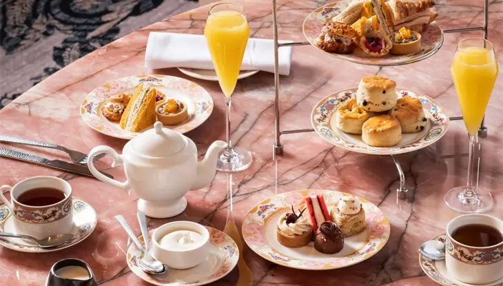 High tea spread with sweets, savouries, and mimosas on a pink marble table at Zoe’s in Fairmont Château Laurier, Ottawa.