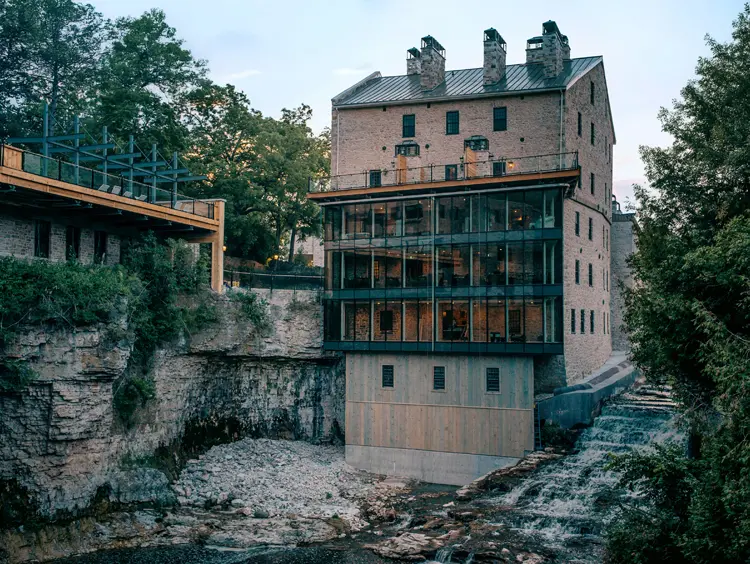 Die historische Elora Mill aus Stein mit einem modernen Glasanbau thront über der Elora-Schlucht und bietet Aussicht auf die felsigen Klippen und das herabstürzende Wasser.