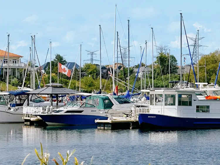 In einem Yachthafen in Clarington, Ontario, liegen Boote vor Anker. Die Masten der Segelboote ragen aus dem Wasser und eine kanadische Flagge weht im Wind.