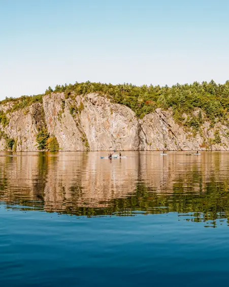  La imponente roca Mazinaw se refleja en el lago Upper Mazinaw, enmarcada por el bosque y la costa arenosa en el parque provincial Bon Echo.