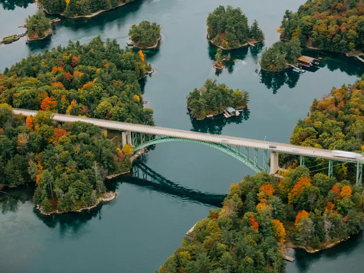 Le pont des Mille-Îles relie l'Ontario et l'État de New York, surplombant des îles boisées aux couleurs automnales et des eaux calmes.